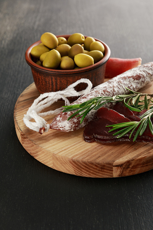 delicious meat platter served with olives on board on black surface
