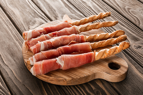 delicious meat platter with grissini and prosciutto on wooden board