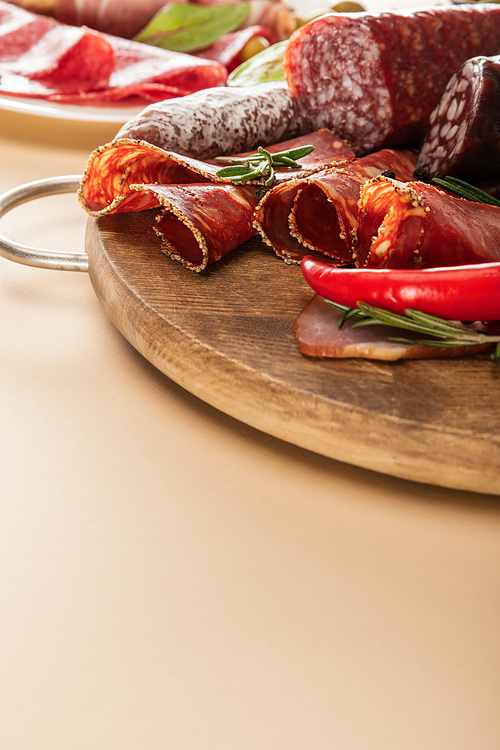 delicious meat platters served with rosemary and chili pepper on wooden board on beige paper