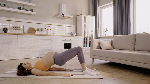 Pregnant woman training on fitness mat at home