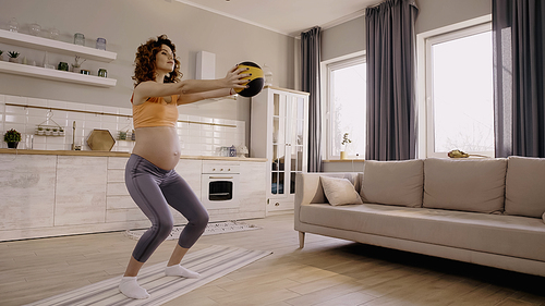 Pregnant woman training with slam ball at home