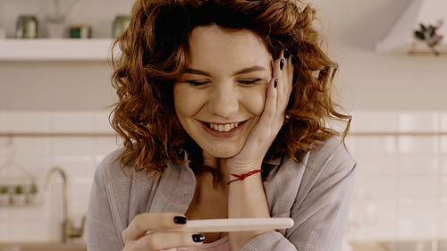 Positive curly woman holding pregnancy test at home