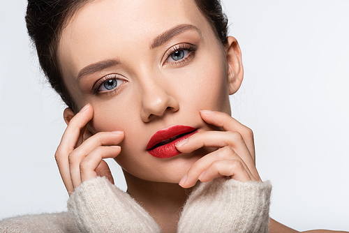 Portrait of young model with red lips touching face and  isolated on white