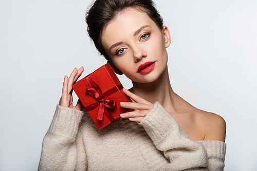 Brunette model in sweater posing with red gift isolated on white