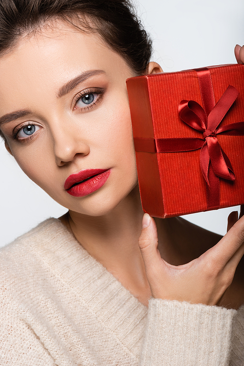 Stylish woman in sweater holding red gift box isolated on white