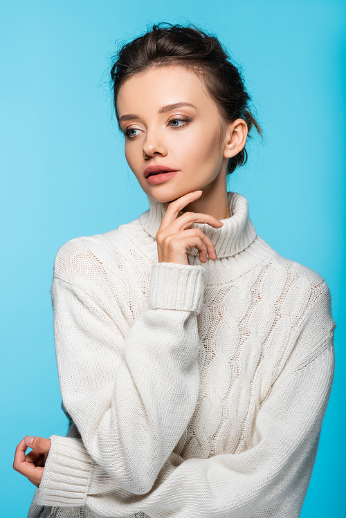 Pretty young model in white knitted sweater isolated on blue
