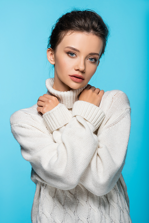 Woman in white sweater posing isolated on blue