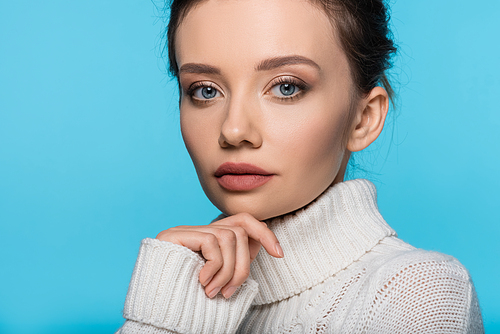 Portrait of young model wearing warm sweater isolated on blue