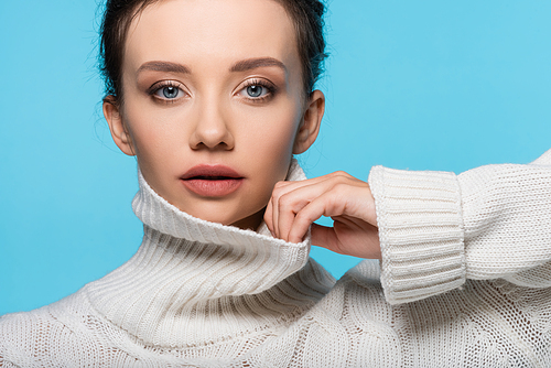 Young model touching collar of knitted sweater isolated on blue