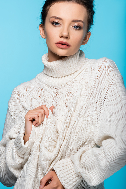 Model  while touching sweater isolated on blue