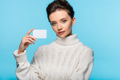 Model in white sweater holding blank card isolated on blue