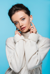 Pretty woman in earphone and sweater  isolated on blue