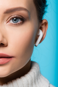 Cropped view of woman in blurred wireless earphone  isolated on blue