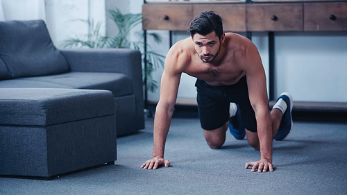 muscular sportsman doing press ups on floor at home