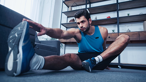 muscular young sportsman stretching at home