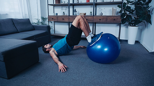 bearded sportsman training on blue fitness ball at home