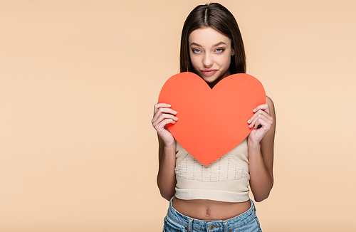 brunette woman in crop top holding paper heart isolated on beige