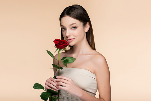 young woman with bare shoulders holding red rose isolated on beige