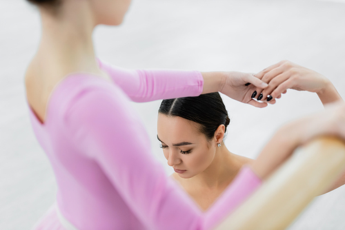ballet teacher near blurred girl during training in dance studio