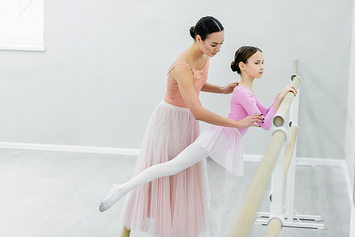 slim girl training in dance studio near young ballet master