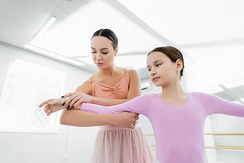 dance teacher assisting preteen girl learning in ballet school
