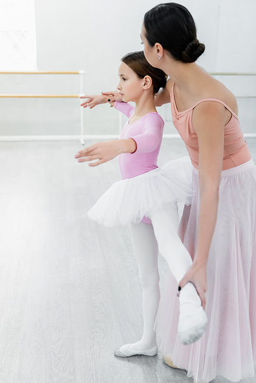 side view of girl learning choreographic elements near ballet master