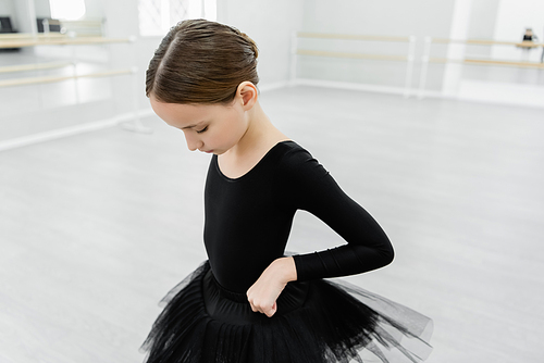 girl adjusting black tutu while training in ballet school