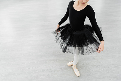 cropped view of girl in black ballet costume rehearsing in dancing hall