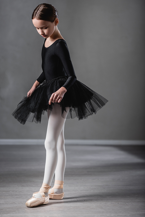 full length view of girl in black tutu dancing in ballet studio