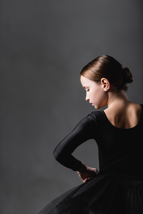 back view of girl in black ballet costume on grey background