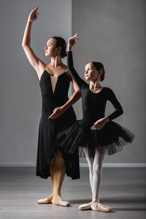 full length view of ballet master showing choreographic elements to girl in black tutu