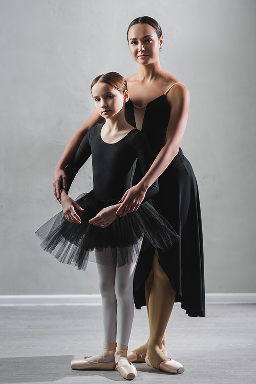 full length view of ballet teacher and girl in tutu  during rehearsal