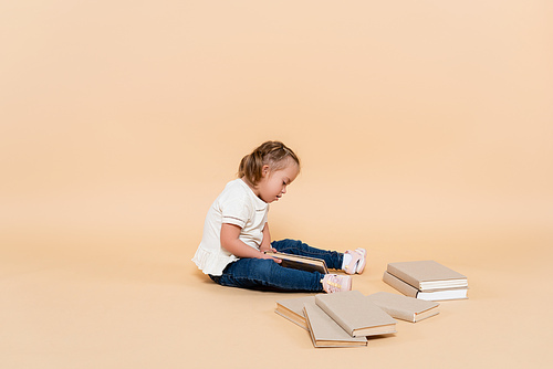 kid with down syndrome sitting near books on beige