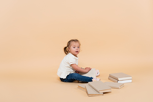girl with down syndrome sitting near books on beige