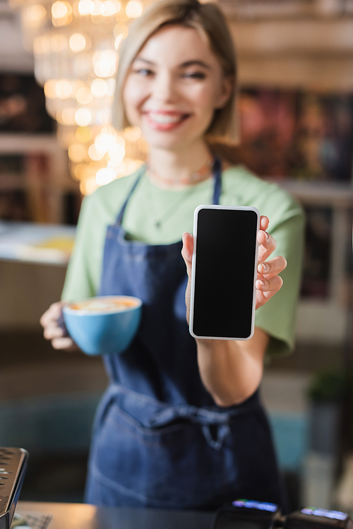 Cellphone with blank screen in hand of barista with cup in cafe