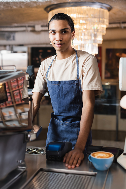 African american barista  near coffee and coffee machine in cafe