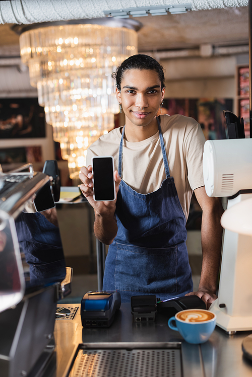 Young african american barista showing smartphone with blank screen near coffee in cafe