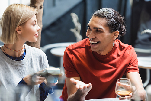 Smiling interracial couple holding coffee in cafe