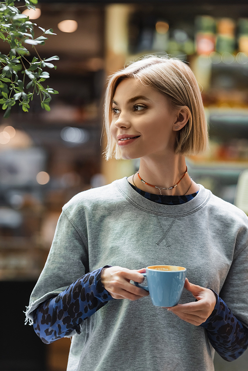 Smiling woman holding cup of coffee in cafe