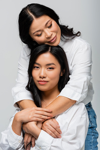 loving asian mother hugging young daughter isolated on grey
