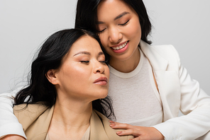 happy asian young daughter hugging mother isolated on grey