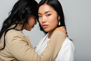 asian mother embracing young daughter isolated on grey