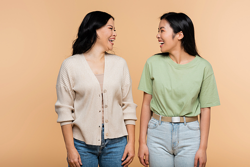 cheerful asian mother and adult daughter looking at each other isolated on beige