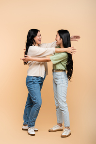 full length of asian with outstretched hands near happy adult daughter on beige