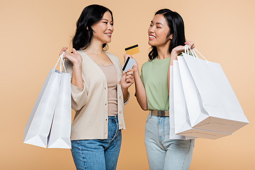 happy asian mother and daughter with shopping bags and credit cards isolated on beige