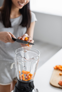 partial view of blurred woman with knife adding cut pumpkin into shaker