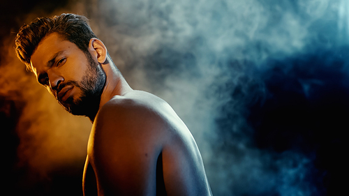 bearded and muscular sportsman  with smoke on black