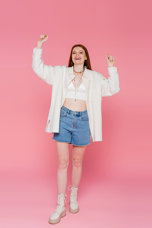 Full length of cheerful and stylish woman  on pink background