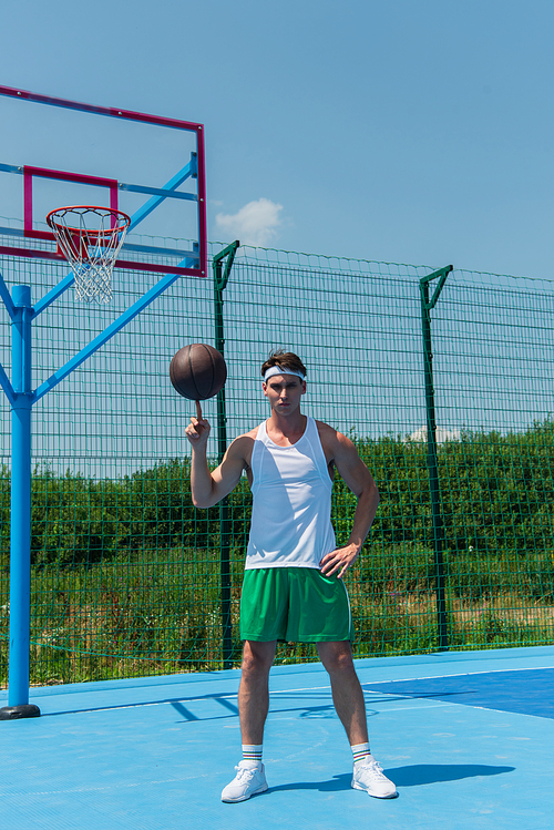 Sportsman holding basketball ball on finger on playground