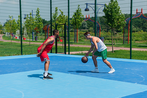 Multiethnic streetball players training with basketball ball on playground